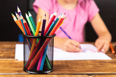 Close-up of desk organizer with girl drawing on table