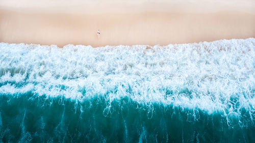 Nature abstract background beautiful sea wave on the sand beach and small tourist couple 