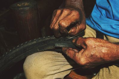 Midsection of man working on tire