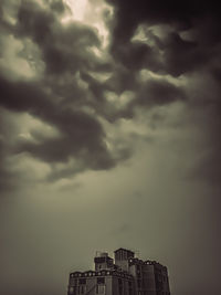 Low angle view of building against storm clouds