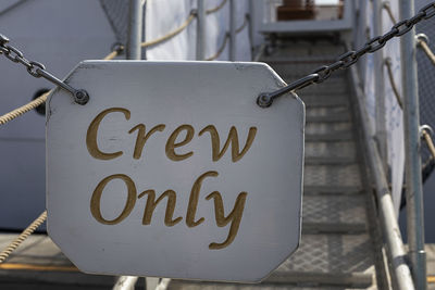 White sign hanging with a chain crew only.