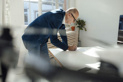 Businessman writing on document at desk in office