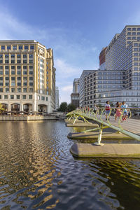 Buildings by river in city against sky