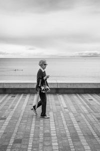 Full length side view of man standing in sea against sky