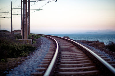 Railroad track by sea against clear sky