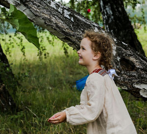 Smiling girl standing by tree trunk