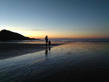 Silhouette man standing on beach against sunset