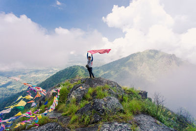 Man with umbrella on mountain against sky