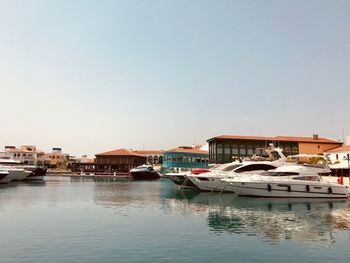 Boats moored at harbor against clear sky