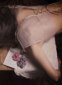 Woman lying face down next to a letter and some flowers