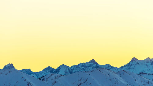Scenic view of snowcapped mountains against clear sky during winter