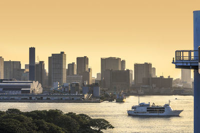 Cruise ship sailing in odaiba bay between daiba park and rainbow bridge at sunset.