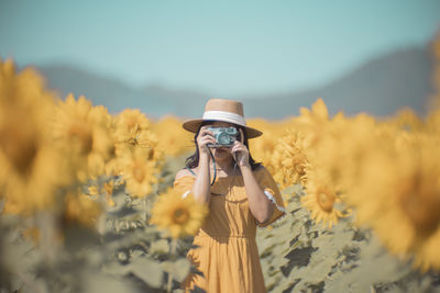 Low angle view of woman photographing against clear sky