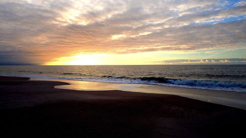 View of beach against cloudy sky during sunset
