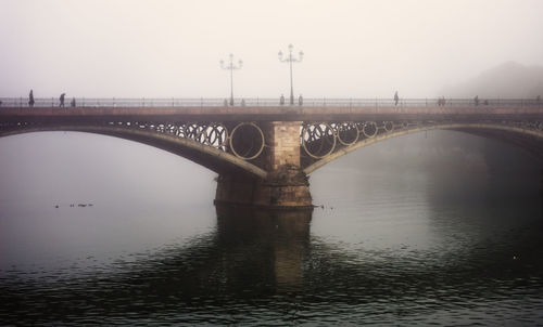 Arch bridge over river against clear sky