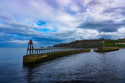 Bridge over river against cloudy sky