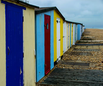 Wooden huts on beach against blue sky