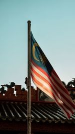 Low angle view of flags against clear blue sky