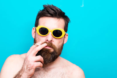 Portrait of shirtless young man against blue background