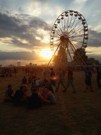 Ferris wheel at amusement park against sky during sunset