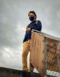 Low angle view of young man standing against sky