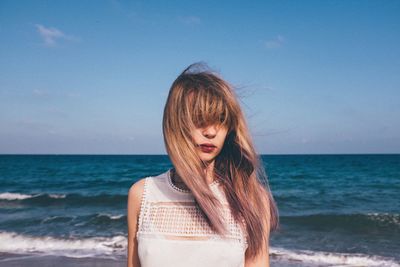 Front view of woman standing at sea shore against sky