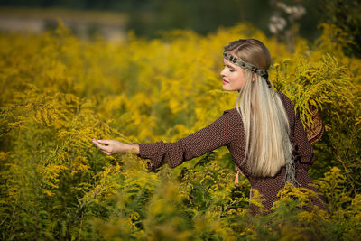 Side view of young woman standing on field