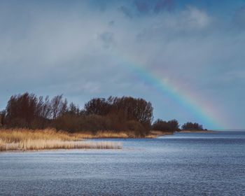 Scenic view of rainbow over lake against sky