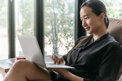 Smiling woman using laptop while relaxing at home