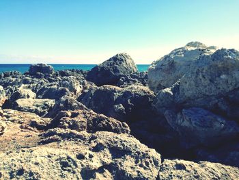 Scenic view of rocks in sea against clear blue sky