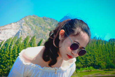 Close-up of woman wearing sunglasses against clear blue sky