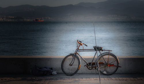 Bicycle by river against mountains