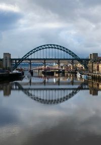 Bridge over river in city against sky