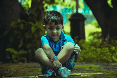 Portrait of cute boy sitting outdoors