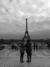 Tourist looking at eiffel tower against cloudy sky
