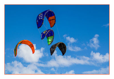 Low angle view of colorful balloons against blue sky