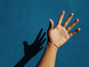 High angle view of human hand against blue wall