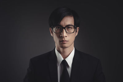 Portrait of young man against black background