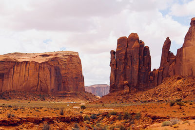 Rock formations on landscape against cloudy sky