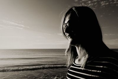 Close-up of young woman at beach against sky