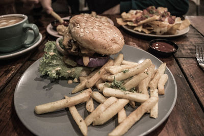 High angle view of burger with french fries in plate on table