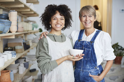 Portrait of smiling females with bowl in pottery class