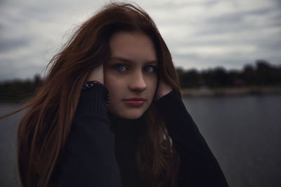 Portrait of young woman looking away against lake