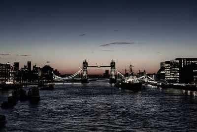 Bridge over river in city against sky during sunset