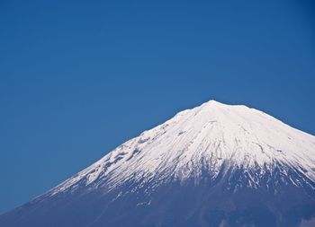 Low angle view of snowcapped mountain against clear blue sky