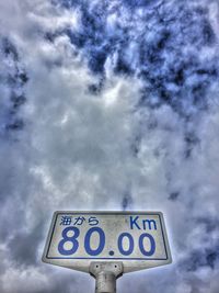 Low angle view of road sign against cloudy sky