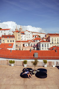 People sitting outside buildings against sky in city