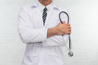 Midsection of doctor standing against wall