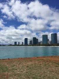 Sea by modern buildings against sky in city