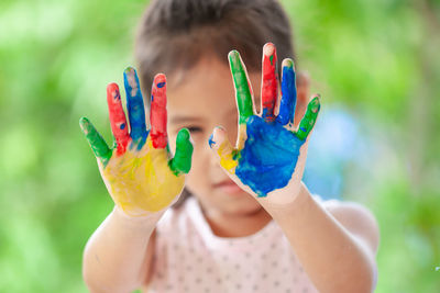 Close-up portrait of smiling girl showing colorful body paint on hands